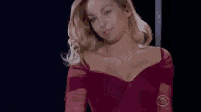 a woman in a red dress is standing on a stage in front of a black background .