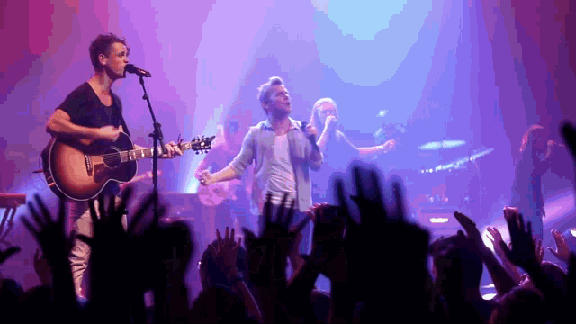 a man singing into a microphone while holding a guitar