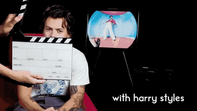 a man sitting in front of a clapper board with the words with harry styles on the bottom