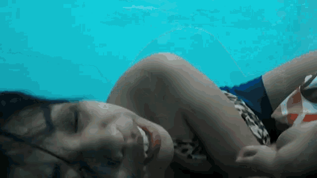 a woman in a bikini is laying in a swimming pool with her eyes closed