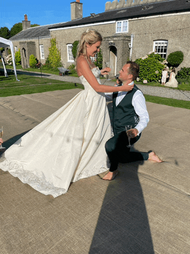 a bride and groom are dancing on a concrete floor