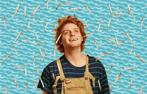a man wearing overalls and a striped shirt is surrounded by cigarette butts