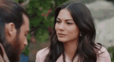 a man and a woman are looking at each other and talking . the woman is wearing a pink jacket .