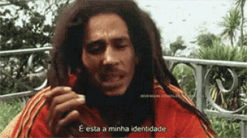 a man with dreadlocks is smoking a cigarette and says " e esta a minha identidade " at the bottom