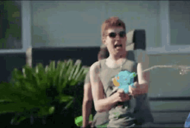 a man wearing sunglasses is holding a water gun and spraying water