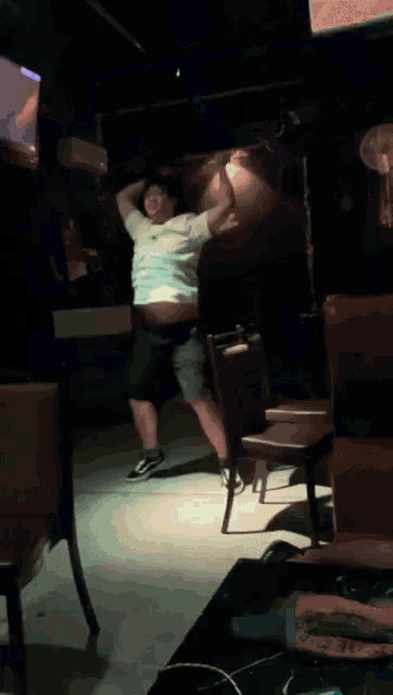 a man in a white shirt with the word coca cola on it is dancing in a dark room