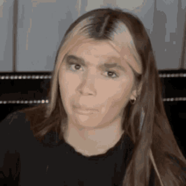 a woman with long hair and blonde streaks is making a funny face and looking at the camera .