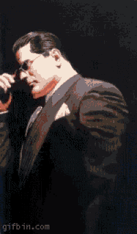 a man in a suit is holding a pair of glasses in his hand