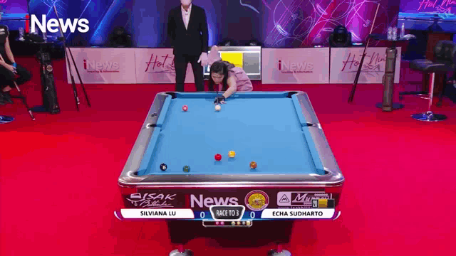 a woman is playing pool on a pool table that is sponsored by news