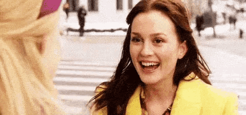 a woman in a yellow jacket is smiling and talking to another woman .