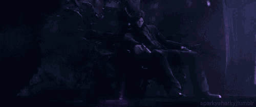 a person is standing in a dark room with purple lights coming out of it .
