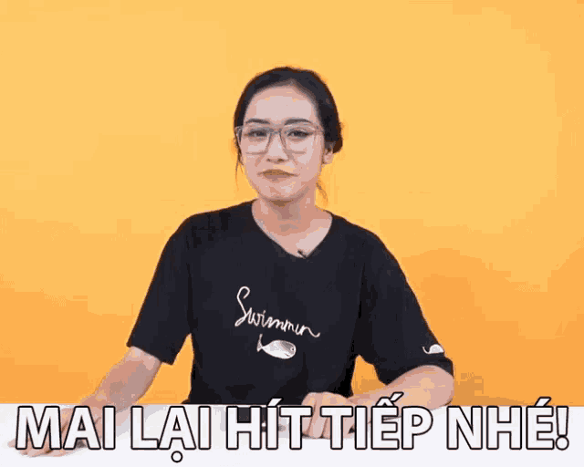 a woman wearing glasses and a black shirt that says ' swimmer ' on it