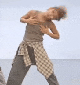 a woman in a plaid shirt is dancing on a beach