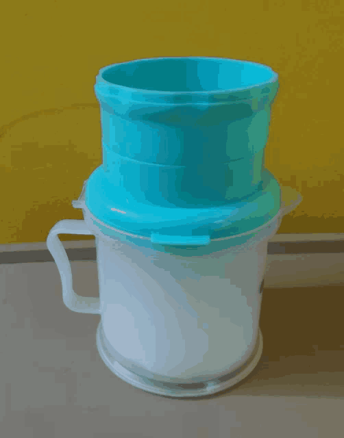 a white plastic container with a blue lid and handle