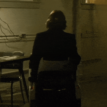 a man sitting in a dark room with a bottle of beer