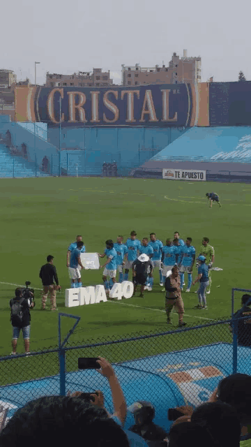 a group of soccer players standing in front of a sign that says cristal