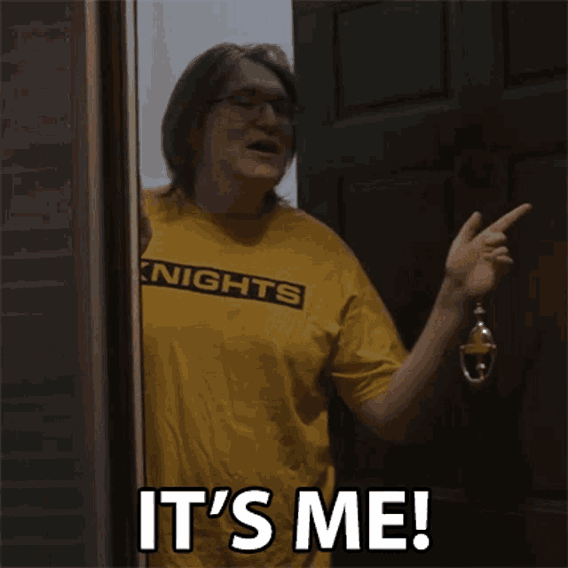 a man in a yellow shirt is standing in front of a door and saying it 's me .