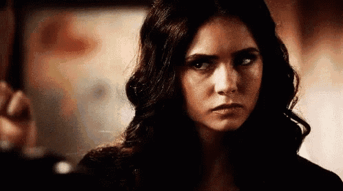 a woman with long dark hair is looking at the camera and making a serious face .