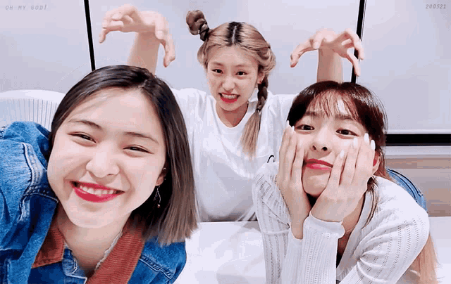 three girls are posing for a picture and one of them is wearing a white shirt with the letter n on it