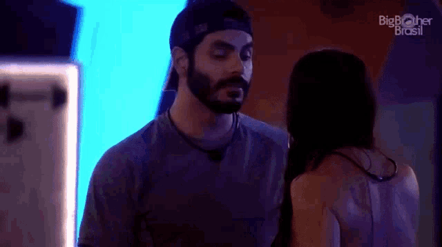 a man with a beard and a woman with long hair are standing next to each other in a dark room .