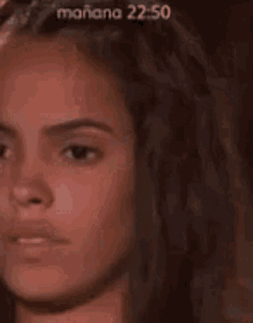 a close up of a woman 's face with a blurred background and the words mañana 22:05 on the bottom .
