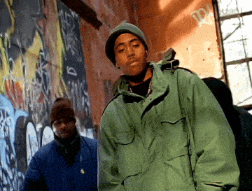 a man in a green jacket is standing in front of a graffiti wall