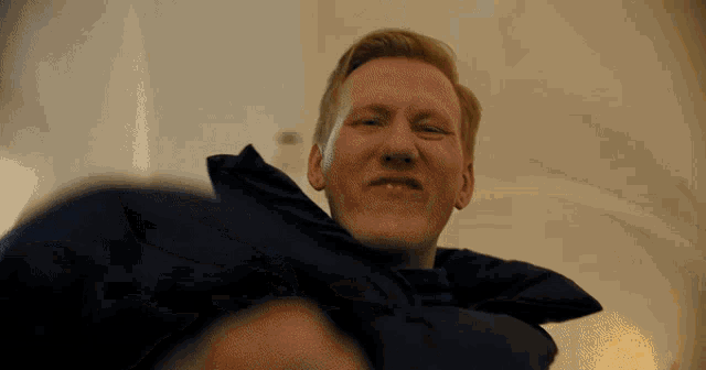 a man wearing a blue jacket looks down at something