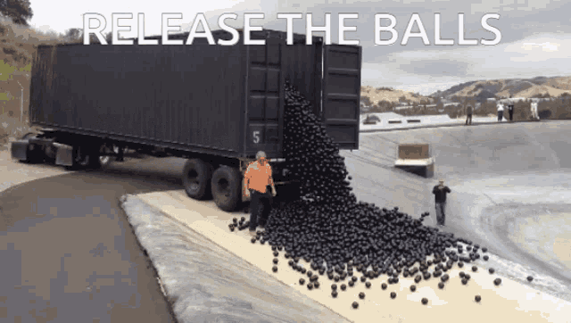 a man is standing in front of a large black truck that says release the balls