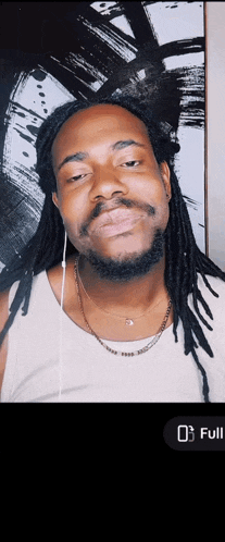 a man with dreadlocks and a beard is wearing headphones and a necklace