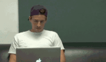 a man wearing a purple hat is using an apple laptop computer