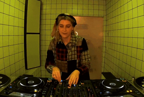 a woman in a plaid shirt is playing music on a dj mixer