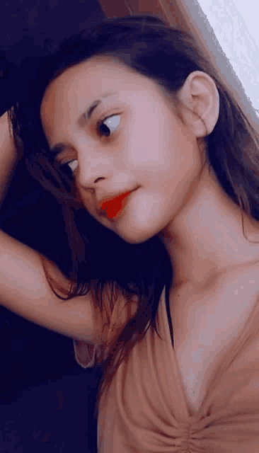 a young girl is taking a selfie with her hand in her hair and red lipstick .