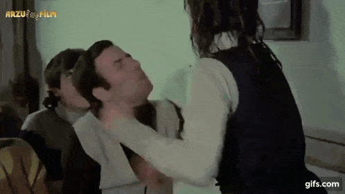 a woman is holding a man 's neck in a scene from a movie