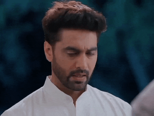 a man with a beard and a white shirt is looking down