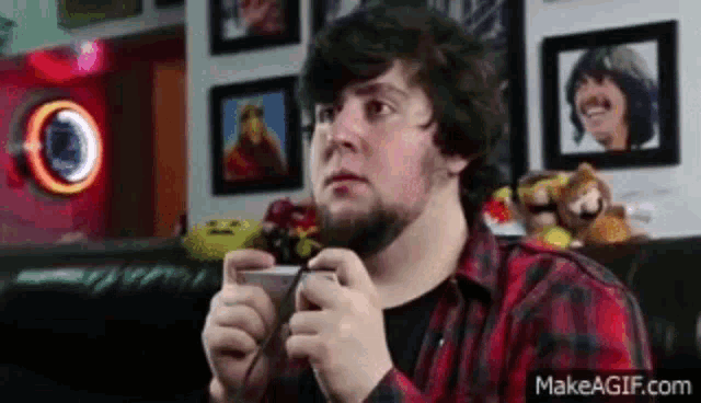 a man with a beard is playing a video game on a couch .