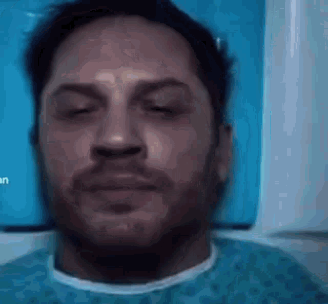 a close up of a man 's face with his eyes closed and a beard .