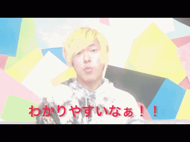a man with blonde hair stands in front of a colorful background and says ' ! '