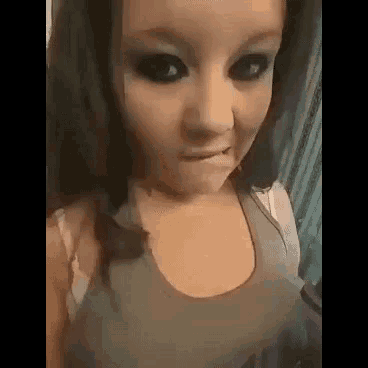 a young girl with black eyes is making a funny face while wearing a tank top .