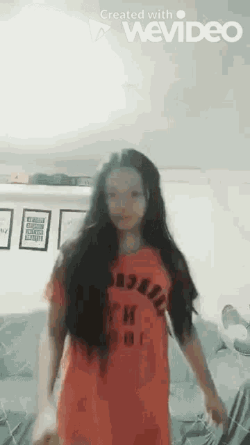 a girl with long hair is wearing a red shirt that says ' basketball ' on it .