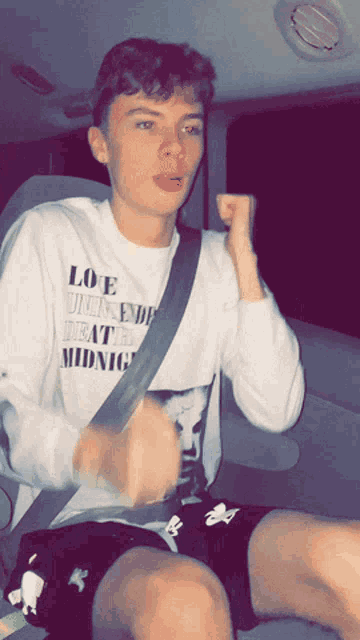 a young man wearing a white shirt that says love until the death of midnight