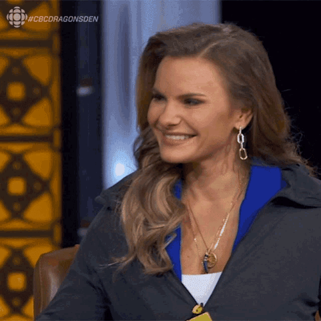 a woman is smiling in front of a cbs dragonsden logo