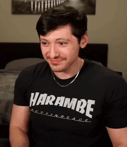 a man wearing a black shirt that says harambe rest in peace on it