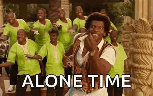 a man is dancing in front of a group of people with the words `` alone time '' written above him .