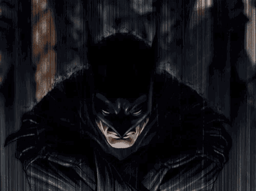 a close up of a man in a batman costume standing in the dark .