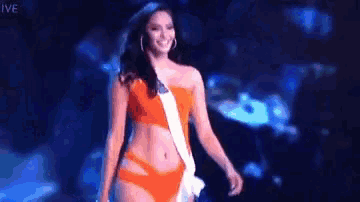a woman in a bikini is walking on a stage at a pageant .