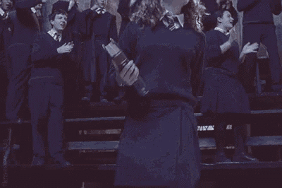 hermione granger is holding a book in front of a crowd of people in a choir .