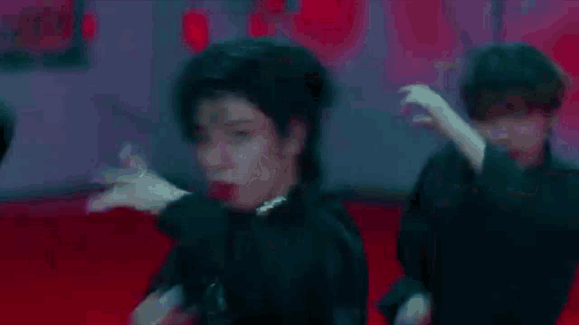 a group of people are dancing on a red carpet in a dark room .
