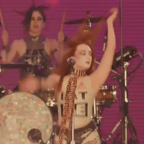 a woman singing into a microphone while wearing a shirt that says eat me