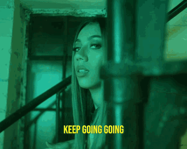 a woman is standing in a dark room with the words keep going going below her