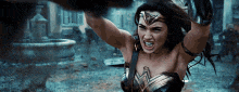 a woman in a wonder woman costume is holding a sword in her hands and screaming .